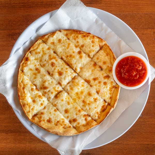 Stone Hot Pizza's cheesy breadsticks, cut into squares, with a side of marinara sauce.