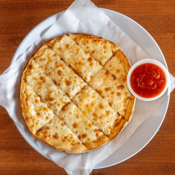 Stone Hot Pizza's cheesy breadsticks, cut into squares, with a side of marinara sauce.