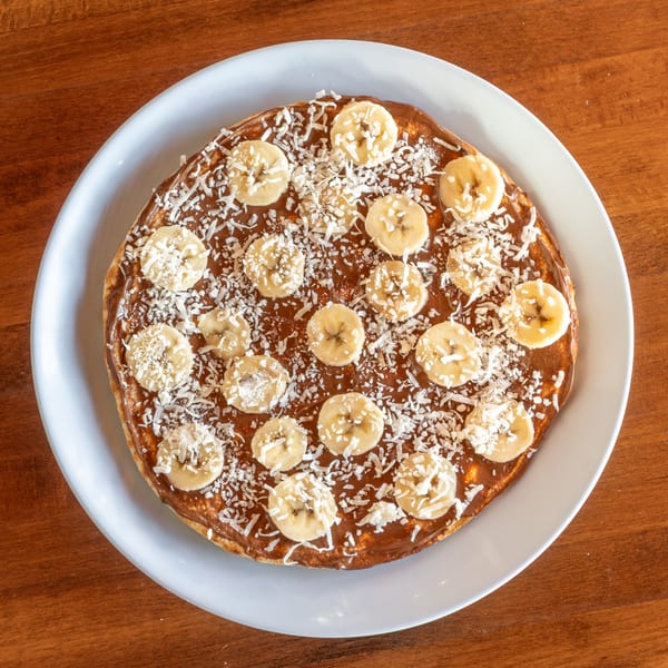 A dessert pizza from Stone Hot Pizza, topped with chocolate spread, banana slices, and shredded coconut.